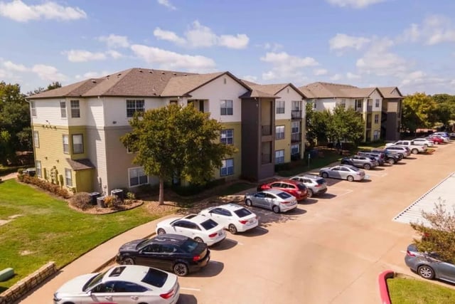 Apartment building with parked cars exterior at University Trails College Station in College Station Student Accommodation