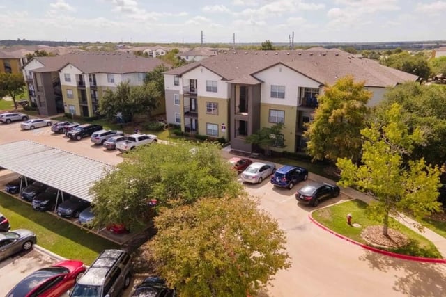 Apartment buildings with cars parked exterior at University Trails College Station in College Station Student Accommodation