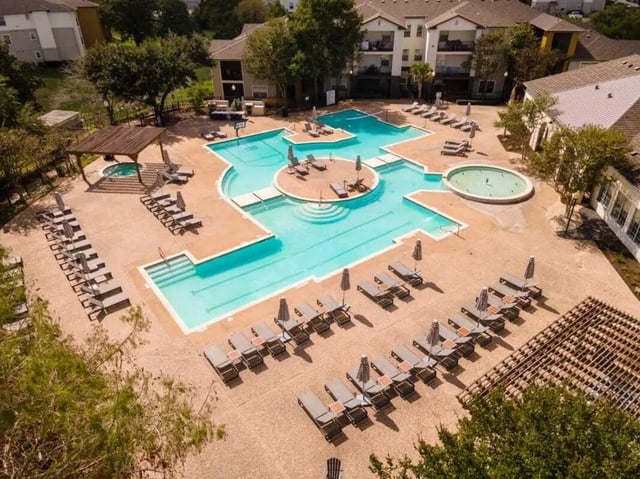 Loungers and umbrellas around pool and jacuzzi exterior at University Trails College Station in College Station Student Accommodation