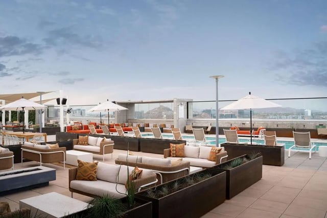 Outdoor lounge area with sofas pool and umbrellas exterior at The Carmin in Tempe Student Accommodation