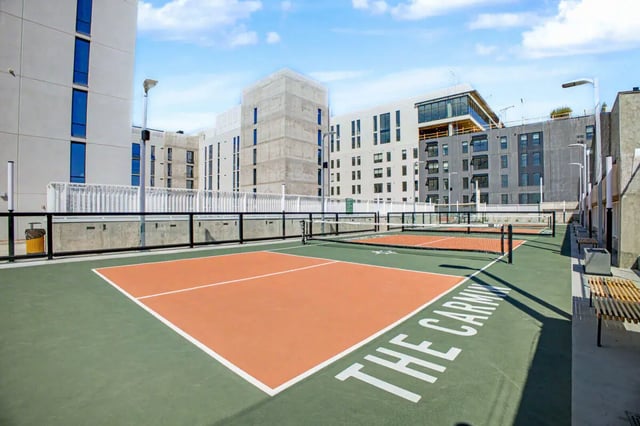Tennis courts with surrounding buildings and seating Playing area Exterior at The Carmin in Tempe Student Accommodation