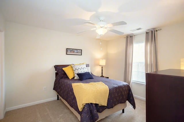 Bed with pillows blanket lamp dresser bedroom at Mountain Valley Apartments in Morgantown Student Accommodation