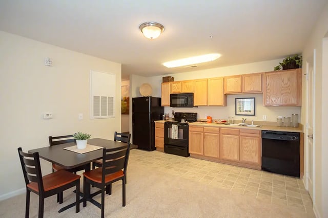 Table chairs refrigerator microwave oven cabinets sink kitchen at Mountain Valley Apartments in Morgantown Student Accommodation