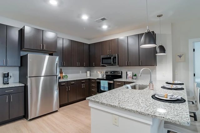 Stainless steel refrigerator microwave dark cabinets granite island kitchen at The Edition on Rosemary in Chapel Hill Student Accommodation