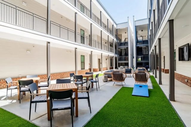 Outdoor seating tables chairs cornhole game exterior at The Edition on Rosemary in Chapel Hill Student Accommodation