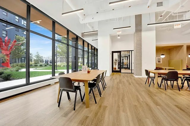Wooden tables chairs large windows common area at Post Chicago Apartments in Chicago Student Accommodation