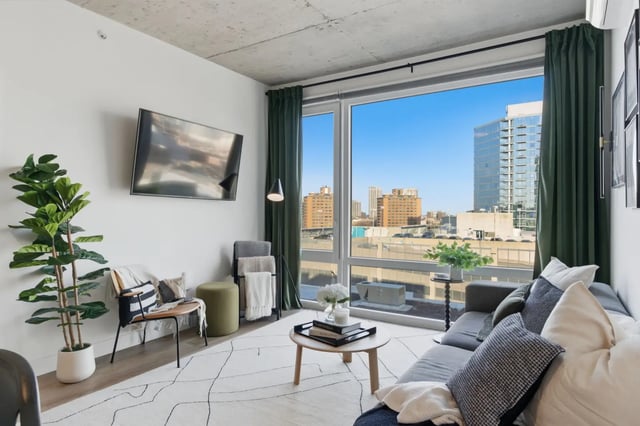 Sofa chair plant television window city view living room at Post Chicago Apartments in Chicago Student Accommodation