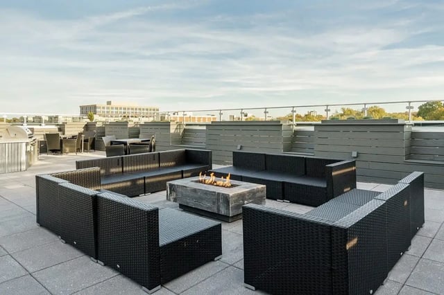 Black sectional sofas around a fire pit exterior at Shortbread Lofts in Chapel Hill Student Accommodation