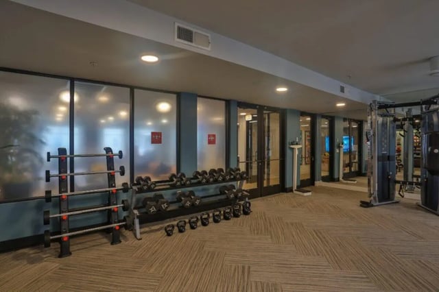 Dumbbells barbells weight machines scale gym interior at Maverick Place Apartments in Arlington Student Accommodation