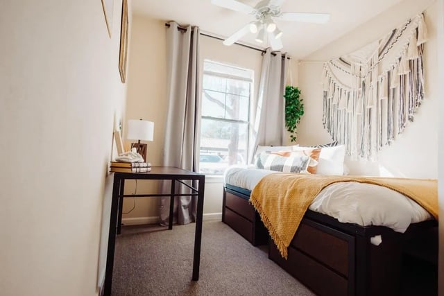 Desk bed pillows plants tapestry bedroom at Maverick Place Apartments in Arlington Student Accommodation