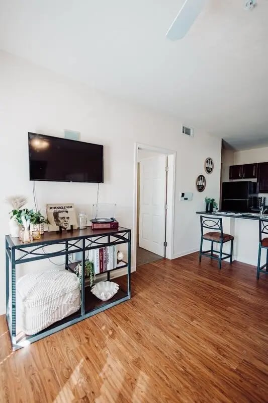 TV record player console ottoman and kitchen living room at Maverick Place Apartments in Arlington Student Accommodation