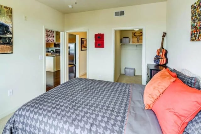 Bed with patterned duvet guitar and open closet bedroom at Venue On Guadalupe in Austin Student Accommodation