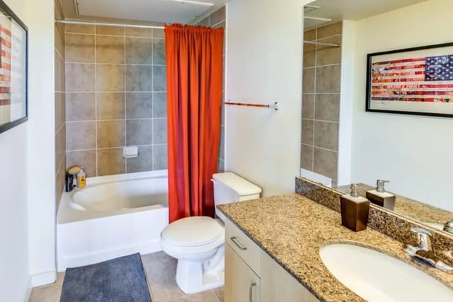 Toilet bathtub orange curtain granite counter bathroom at Venue On Guadalupe in Austin Student Accommodation