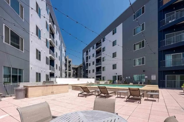 Pool lounge chairs tables and buildings exterior at Venue On Guadalupe in Austin Student Accommodation