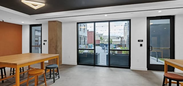 Wooden table stools and large windows showing patio area common room at Parc View at Commonwealth in Richmond Student Accommodation