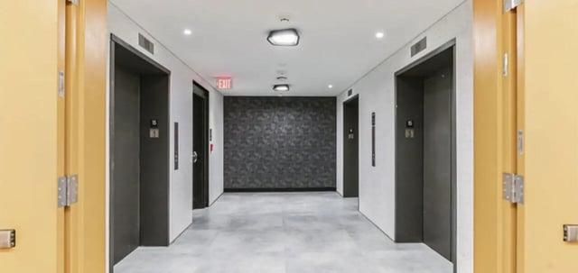 Elevator bank with patterned wall and exit sign hallway at Parc View at Commonwealth in Richmond Student Accommodation