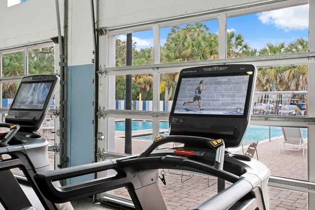Treadmills with screens by pool exterior at Venue at North Campus in Tampa Student Accommodation