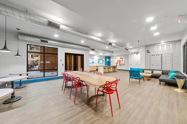 Large dining table red chairs sectional sofa common area at Signature 1505 in Raleigh Student Accommodation