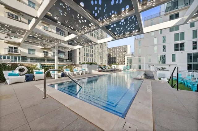 Pool with lounge chairs and modern building exterior at Signature 1909 in Austin Student Accommodation