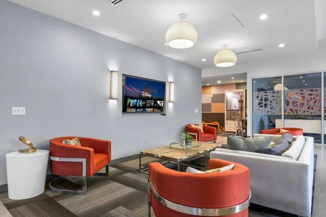 Orange chairs white sofa TV Disney living room at Signature 1909 in Austin Student Accommodation
