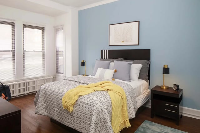 Bed with yellow throw pillows and art bedroom at Hamilton Court in Philadelphia Student Accommodation