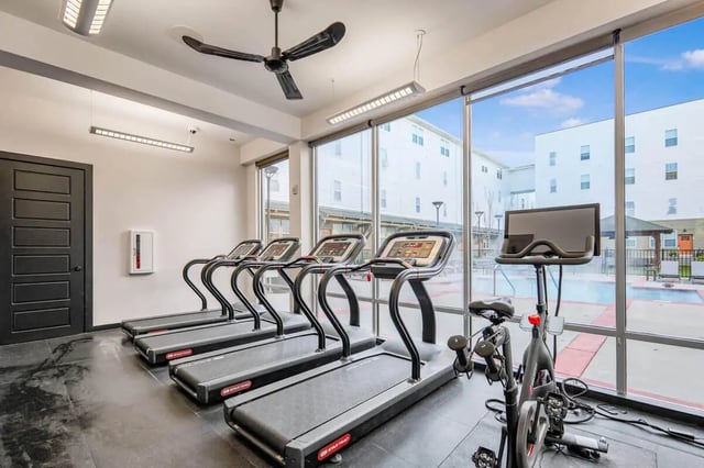 Treadmills exercise bike near swimming pool Fitness room at Hannah Townhomes & Lofts in East Lansing Student Accommodation