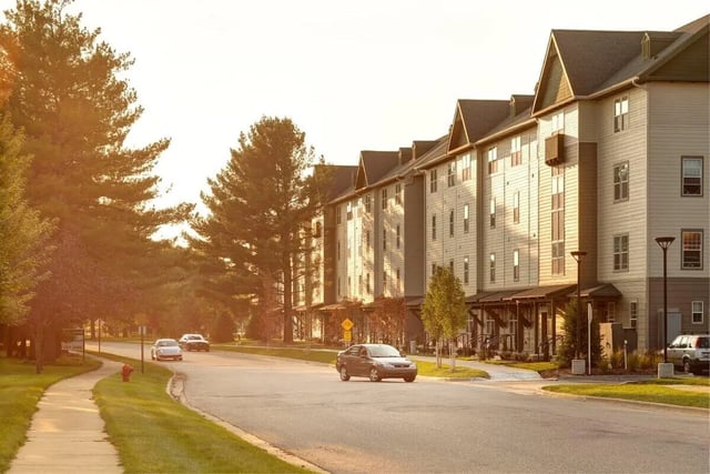 Apartment buildings with cars parked outside exterior at Hannah Townhomes & Lofts in East Lansing Student Accommodation