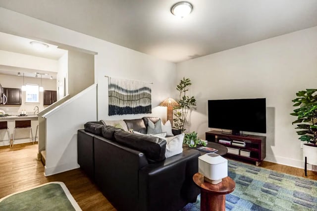 Black leather sofa television and rug living room at Hannah Townhomes & Lofts in East Lansing Student Accommodation