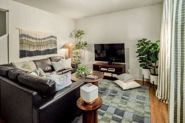 Leather sectional couch with pillows and tapestry living room at Hannah Townhomes & Lofts in East Lansing Student Accommodation