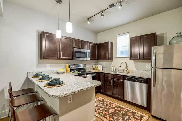 Modern kitchen with dark cabinets granite countertop and island kitchen at Hannah Townhomes & Lofts in East Lansing Student Accommodation