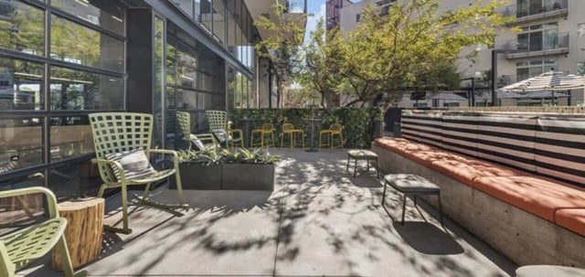 Green chairs concrete planters yellow stools outdoor seating area at Vertex Apartments in Tempe Student Accommodation