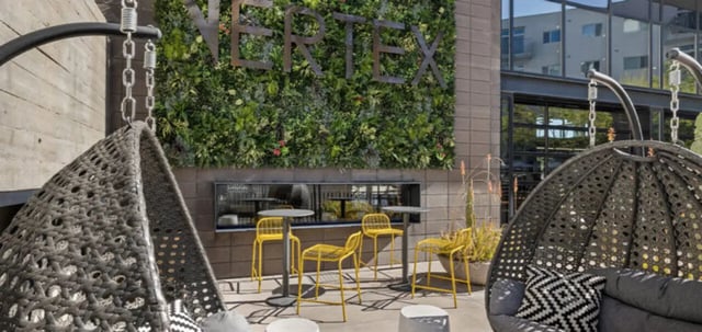 Hanging chairs and seating area with green wall exterior at Vertex Apartments in Tempe Student Accommodation