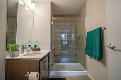 Sink vanity glass shower green towels bathroom at Landmark on Grand River in East Lansing Student Accommodation