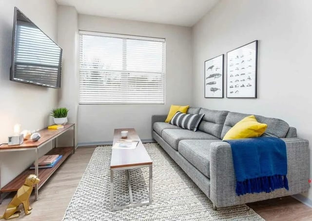 Gray sectional couch with yellow pillows and blue throw living room at Muse on Main in Pullman Student Accommodation