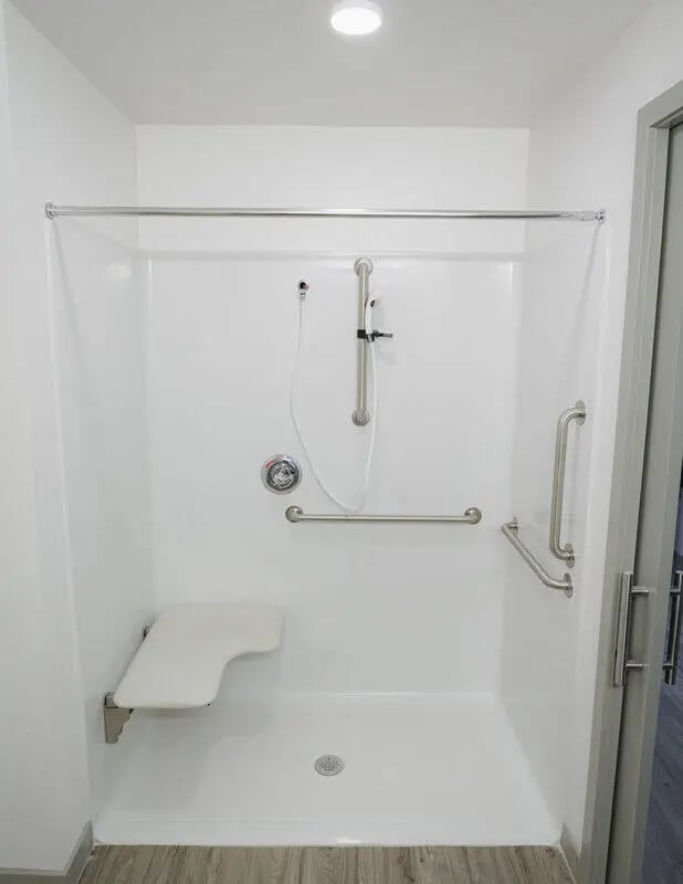 Shower stall with seat grab bars and shower head bathroom at Merced Station in Merced Student Accommodation