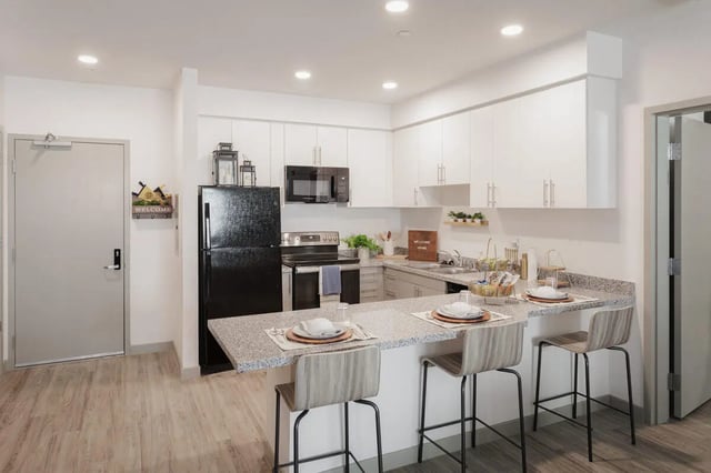 Kitchen with black refrigerator and island kitchen area at Merced Station in Merced Student Accommodation