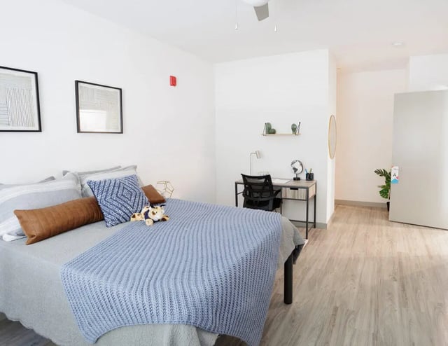 Bed with blue blanket desk and chair bedroom at Merced Station in Merced Student Accommodation