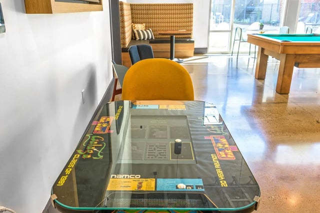 Arcade game table with yellow chair playing area at Merced Station in Merced Student Accommodation