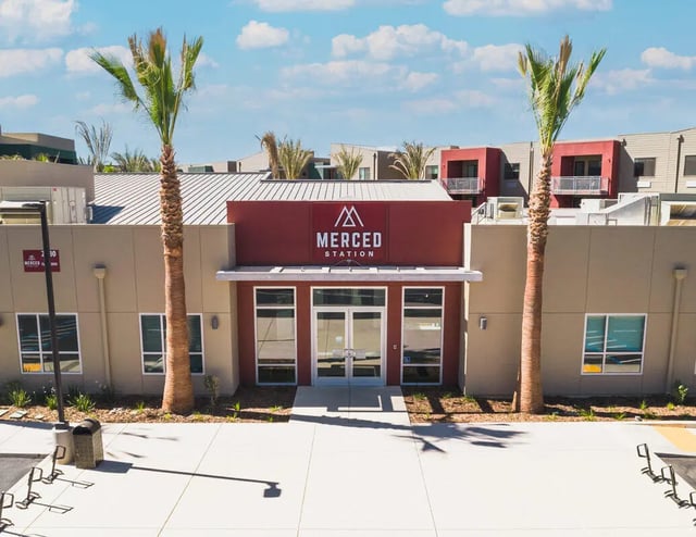 Building entrance with palm trees and windows exterior at Merced Station in Merced Student Accommodation