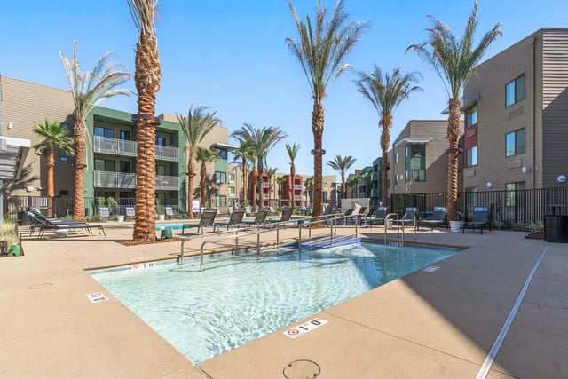 Swimming pool with lounge chairs and palm trees exterior at Merced Station in Merced Student Accommodation