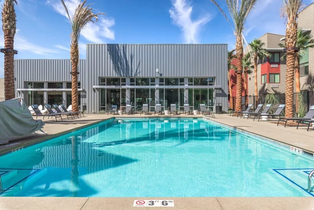 Pool chairs lounge furniture palm trees exterior at Merced Station in Merced Student Accommodation