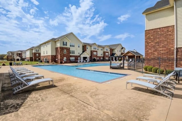 Loungers and pool near apartment buildings exterior at Mustang Village in Wichita Falls Student Accommodation