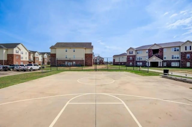 Basketball court with apartment buildings exterior at Mustang Village in Wichita Falls Student Accommodation