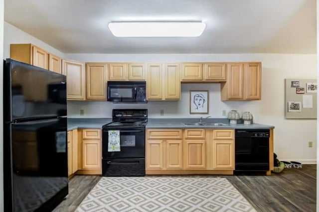 Black refrigerator wood cabinets black stove kitchen at Mustang Village in Wichita Falls Student Accommodation