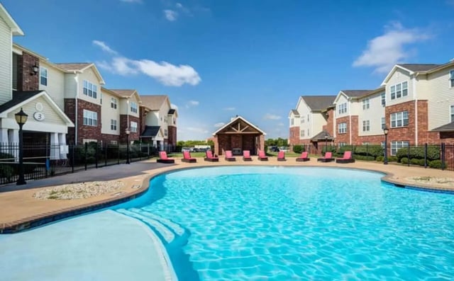 Blue pool with pink loungers exterior at Mustang Village in Wichita Falls Student Accommodation