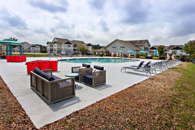 Couches chairs pool lounge chairs buildings pool area at University Village At Clemson in Central Student Accommodation