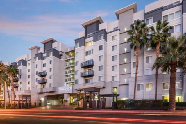 Modern apartment building with balconies and palm trees exterior at University Village Towers in Riverside Student Accommodation
