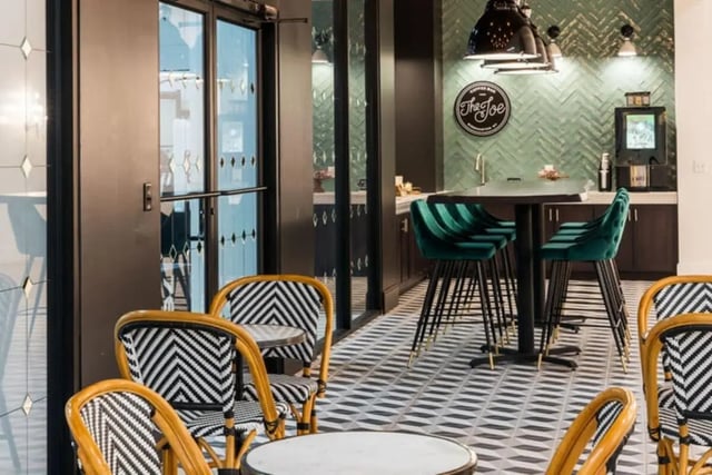 Bar stools and tables by coffee bar living room at Vesper Holdings