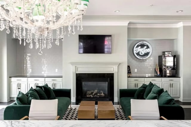 Green sofas fireplace TV coffee bar living room at Vesper Holdings