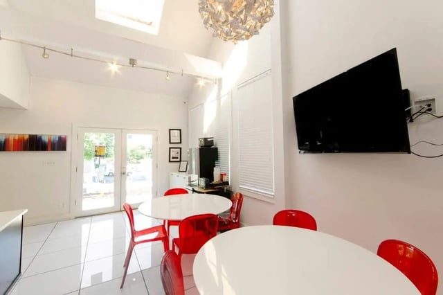 White tables red chairs wall mounted TV communal area at Hawks Pointe II in Lawrence Student Accommodation